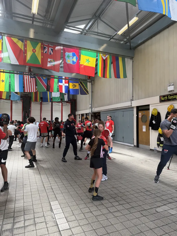 A young boxer trains among boxers and firefighters in the fire station bay