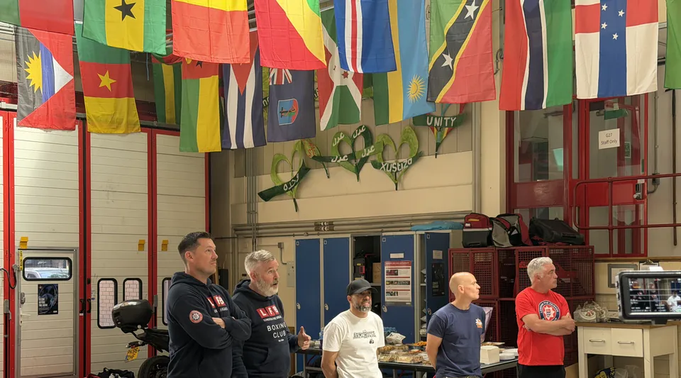 Coaches and firefighters stand together in the fire station during the joint session