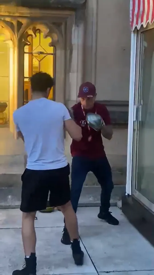 Video of a boxer working the pads with a coach by a lit Gothic window