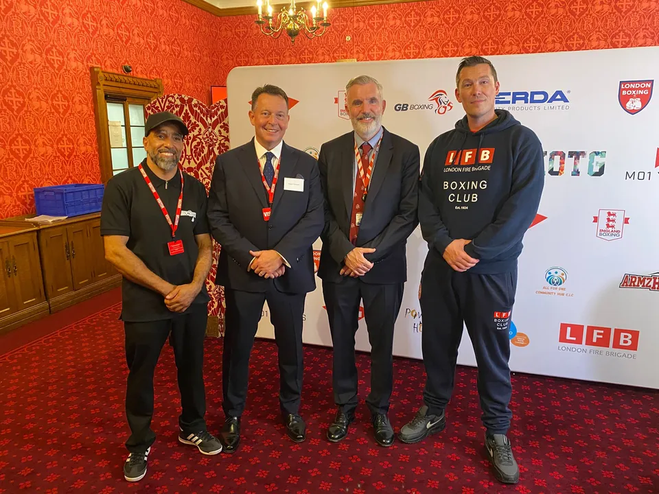 Four guests stand together in front of the event sponsor wall