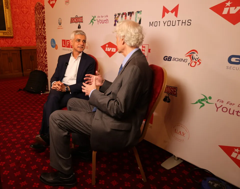 A seated interview in front of the event sponsor wall