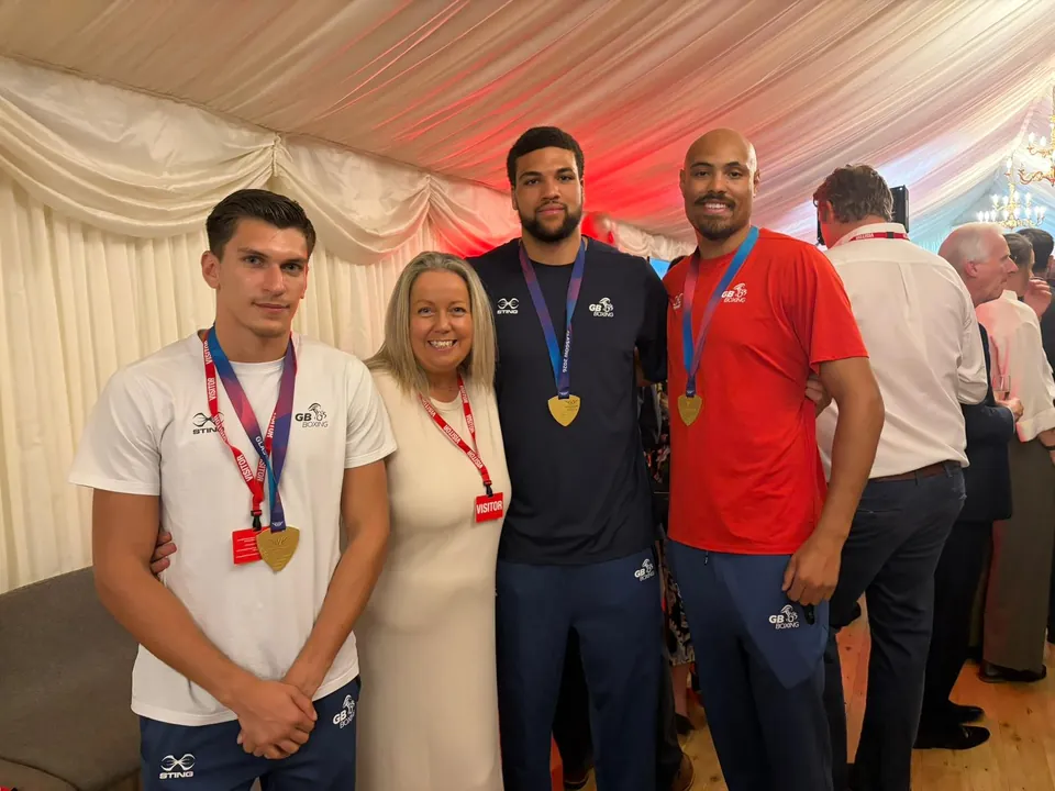Boxers wearing medals pose with a guest at the reception