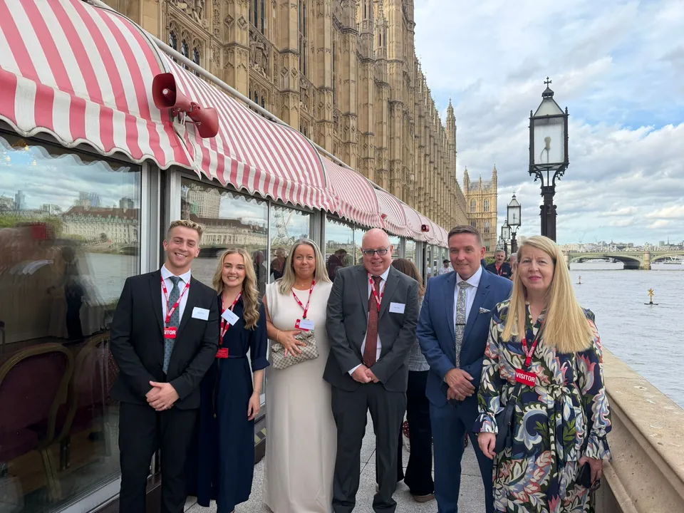 Guests smile together on the River Terrace beneath the Palace of Westminster