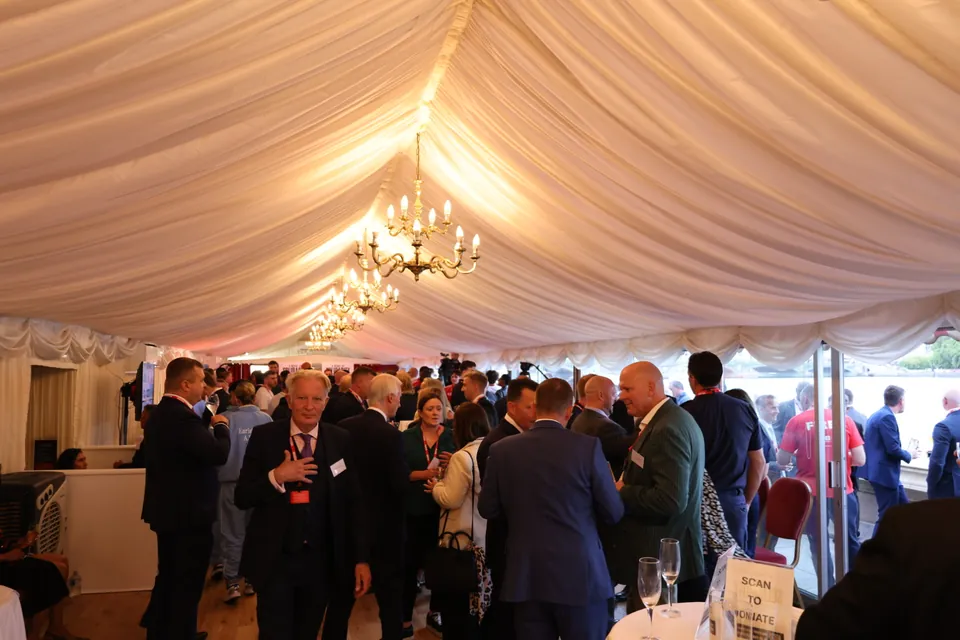 Guests fill the marquee reception beneath chandeliers on the River Terrace
