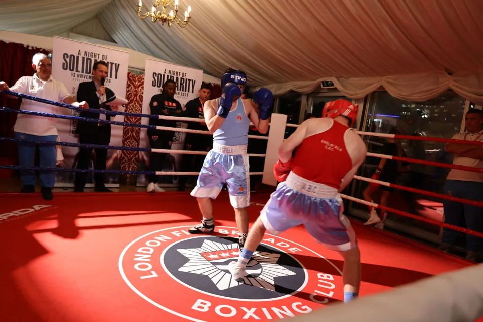 Two boxers with guards up over the London Fire Brigade Boxing Club crest