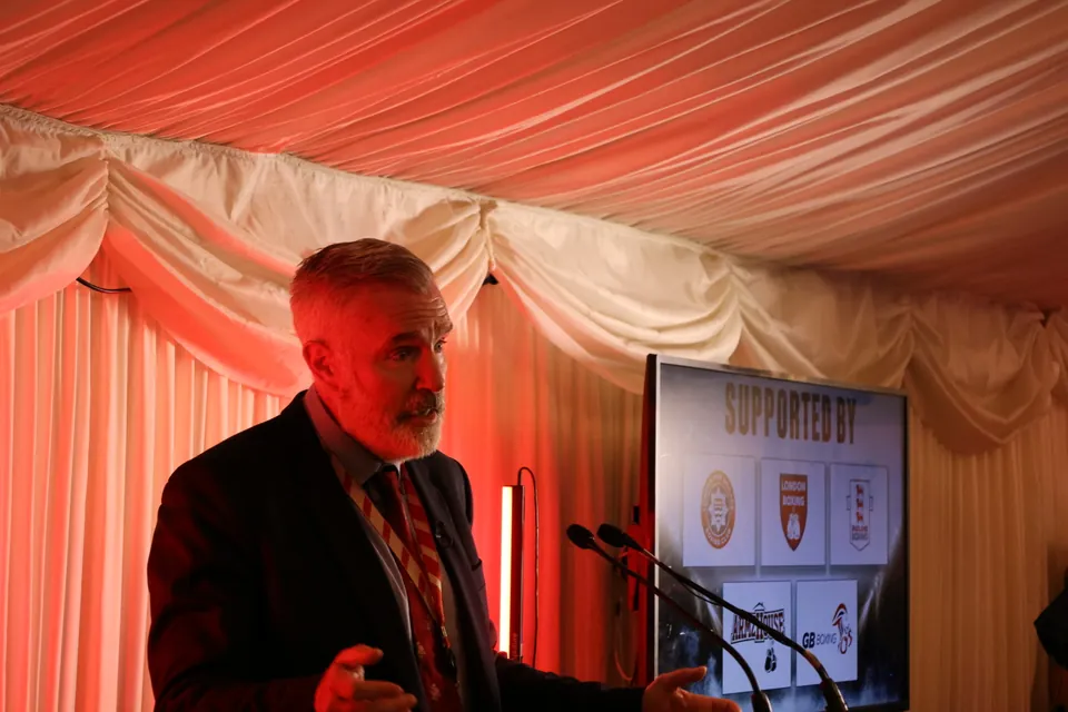 A speaker addresses guests at the lectern beside the Supported By screen